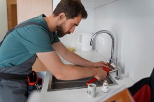 A plumber from a top-tier plumbing company in Orland Park, IL, performing maintenance on a sink.